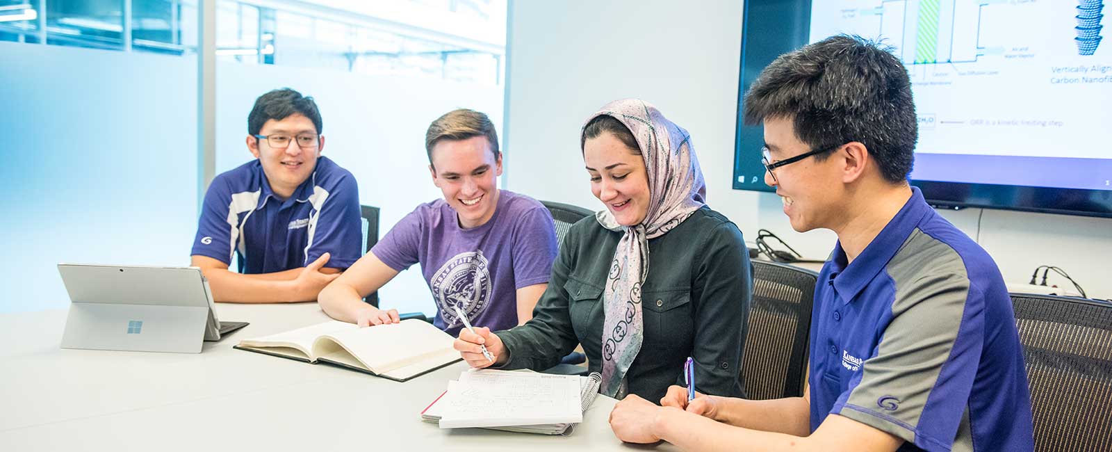 Faculty member sitting with students at a table