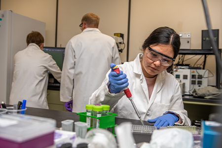 A student pipettes liquid in a lab.